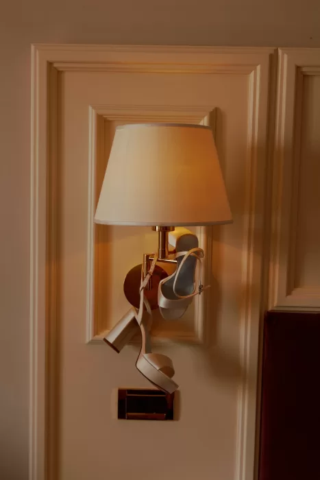 Bridal heels hanging from warm wall lamp in softly lit room at Isola del Garda