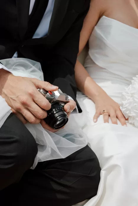 Close-up of couple holding vintage camera with soft bridal textures at Isola del Garda