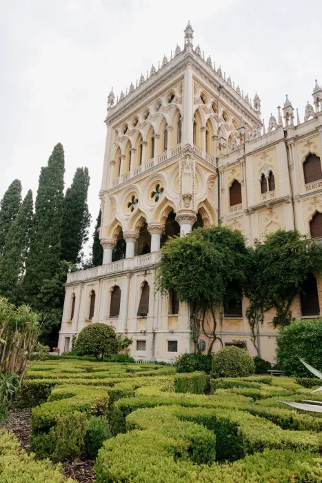 Ornate facade of Isola del Garda villa framed by structured gardens and greenery