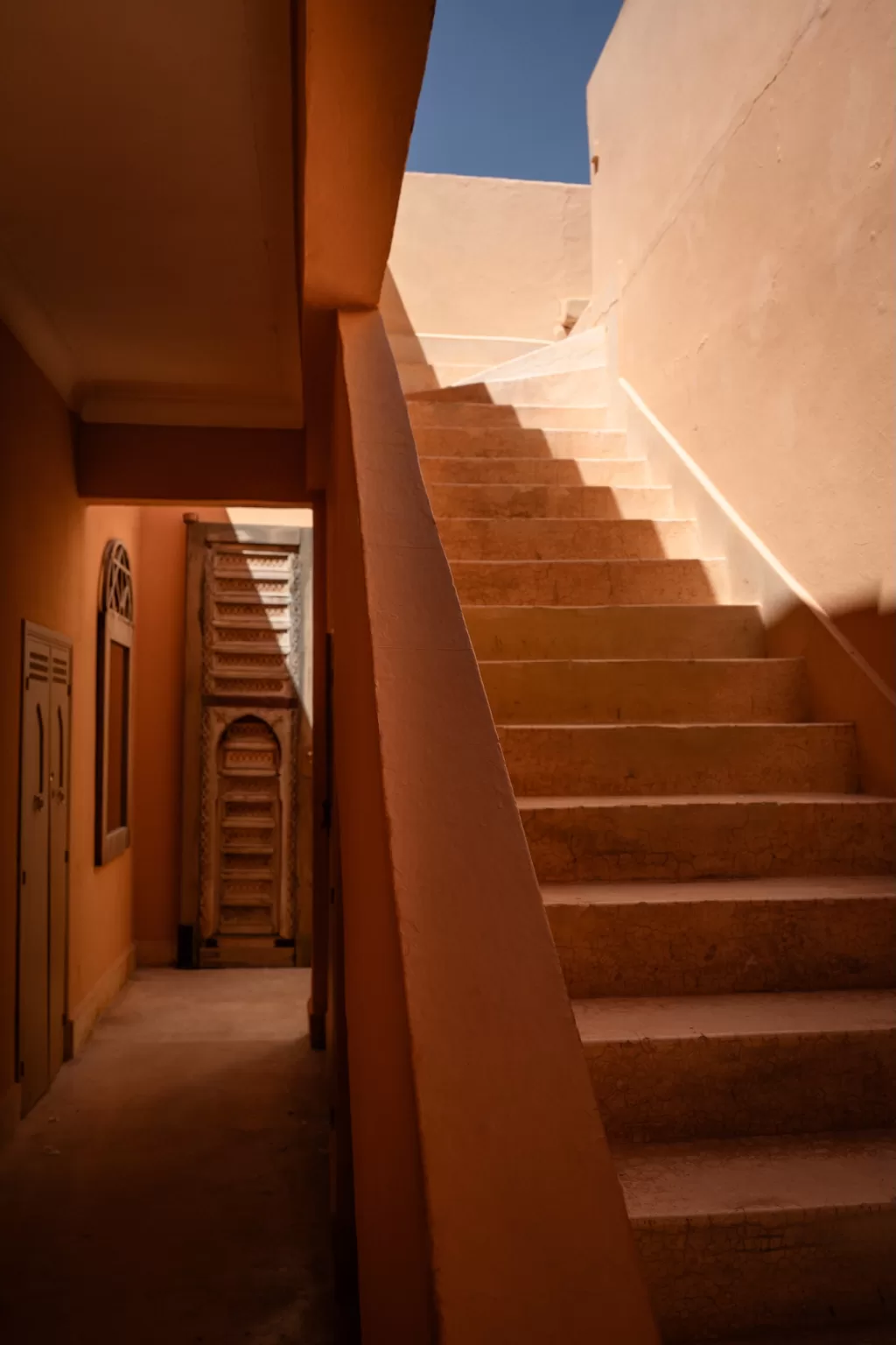Warm sunlit stairway and textured walls creating soft shadows at Jnane Tamsna.