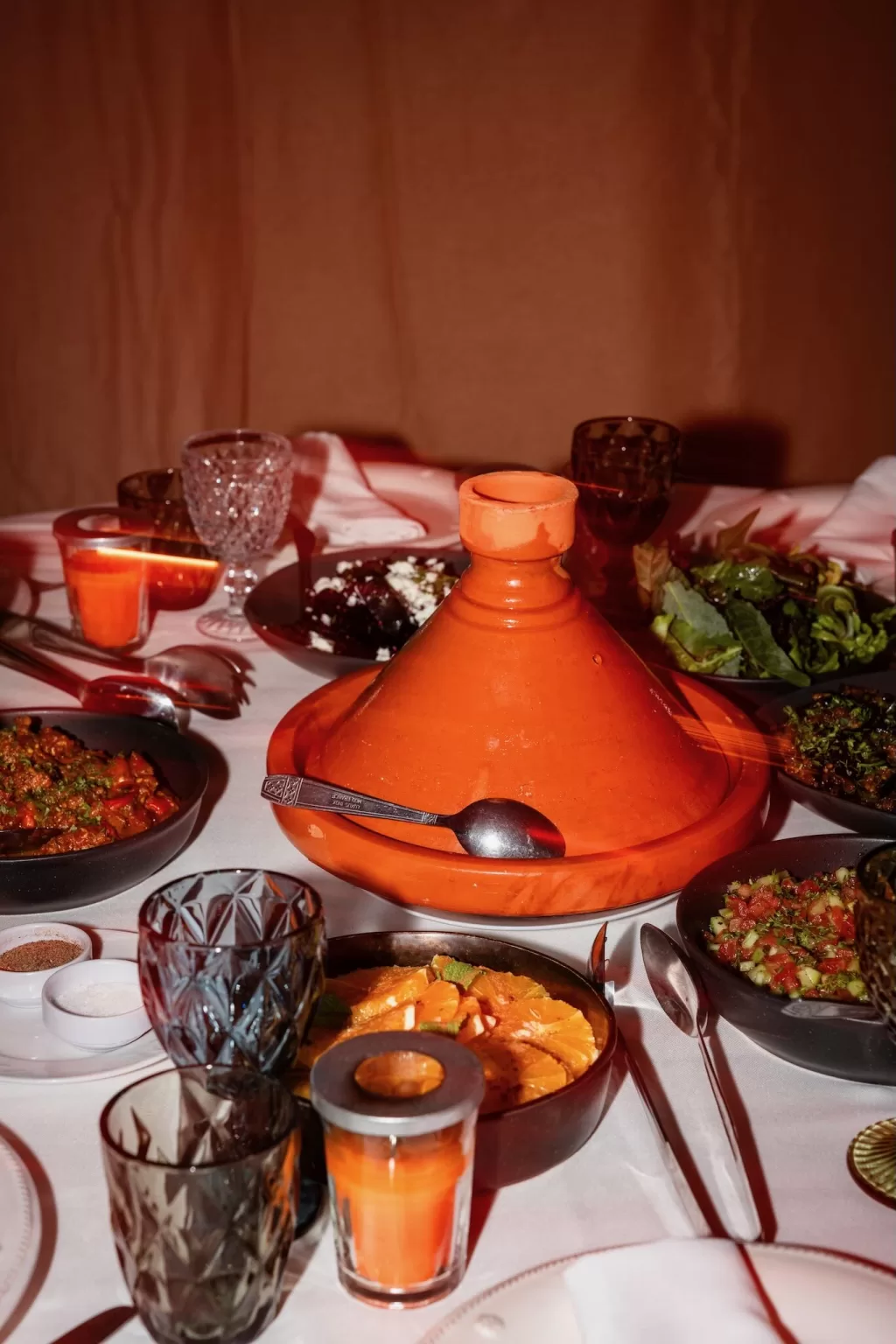 Traditional Moroccan tagine surrounded by colourful salads, candles, and glassware during a wedding dinner at Jnane Tamsna.