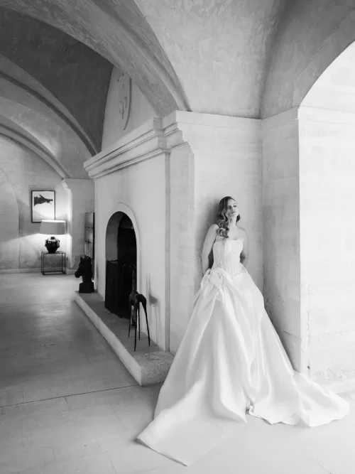 Bride in dramatic gown posing beneath vaulted stone ceilings inside Mas de Chabran.