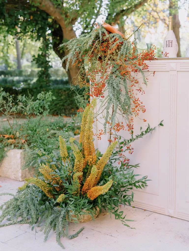 Lush floral arrangement with greenery and orange berries decorating an outdoor bar at Mas de Chabran.