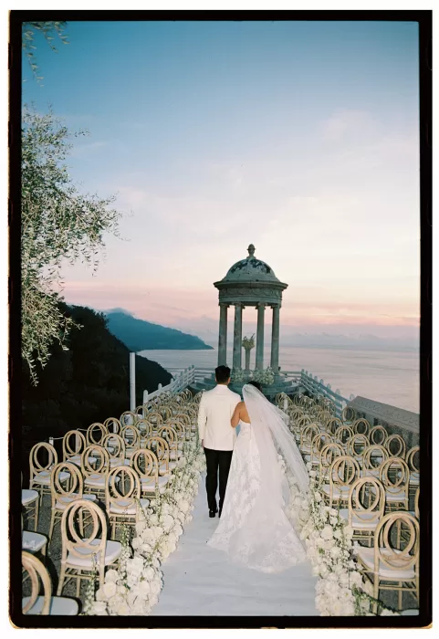 Bride and groom walking toward the temple along aisle at sunset at Son Marroig