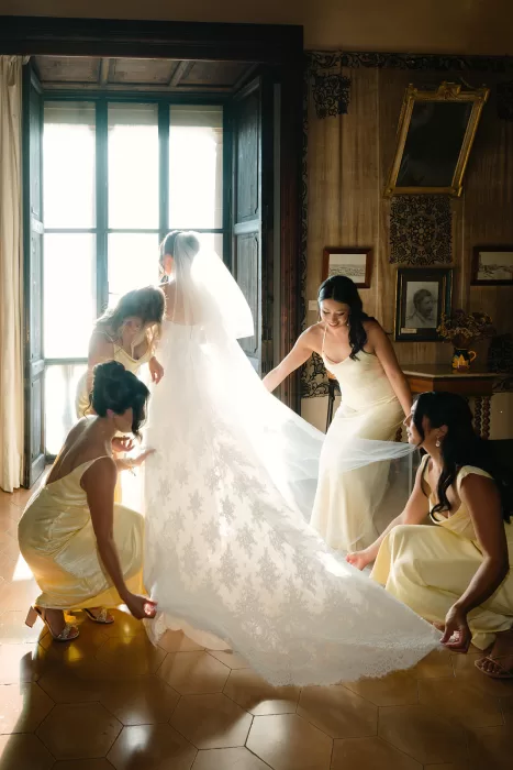 Bride getting ready with bridesmaids adjusting her gown in a sunlit room at Son Marroig