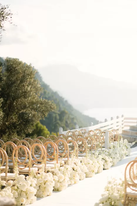 Wedding aisle lined with white flowers and wooden chairs overlooking the Mallorca coastline at Son Marroig