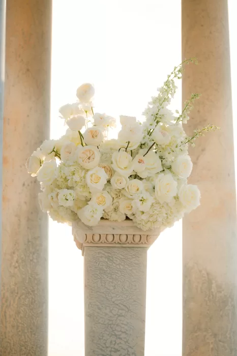 White floral arrangement on a stone pedestal at Son Marroig ceremony overlooking the sea