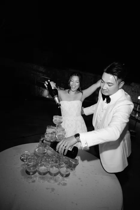 Bride and groom pouring champagne tower during evening celebration at Son Marroig