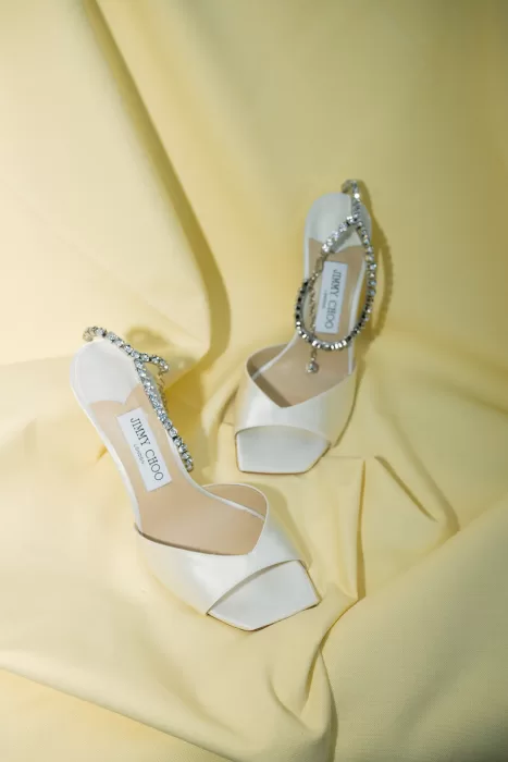 White Jimmy Choo bridal heels styled on soft yellow fabric with a clean, editorial feel