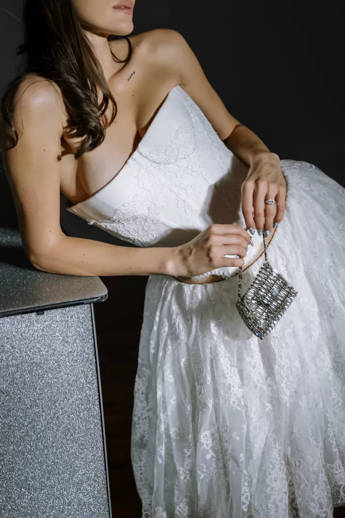 Close-up of bride holding crystal handbag with lace gown and engagement ring details at Studio Sunset Chicago