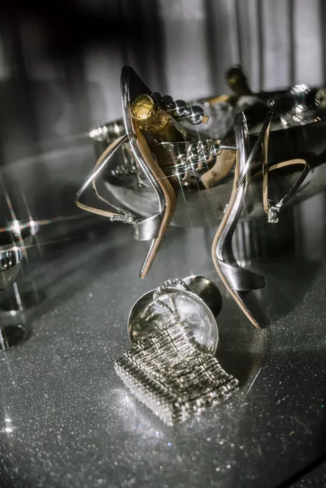 Metallic heels and sparkling jewelry styled on reflective surface with dramatic light at Studio Sunset Chicago