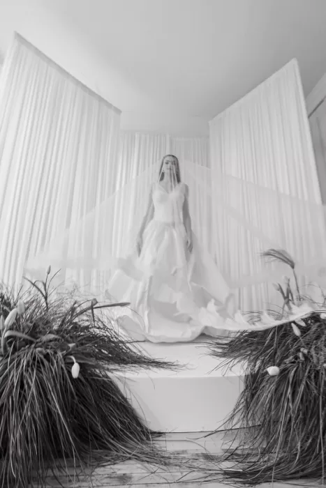 Bride walking through soft draped ceremony backdrop with organic greenery at Studio Sunset Chicago