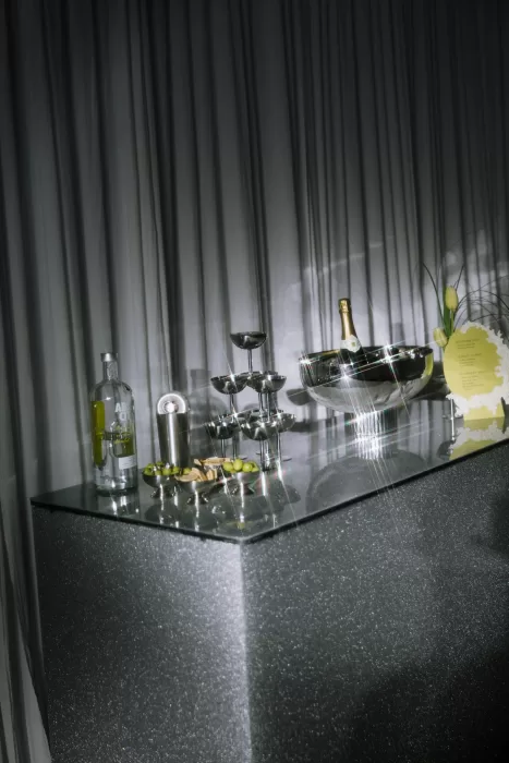 Styled cocktail bar with champagne coupes, olives and reflective textures under dramatic lighting at Studio Sunset Chicago
