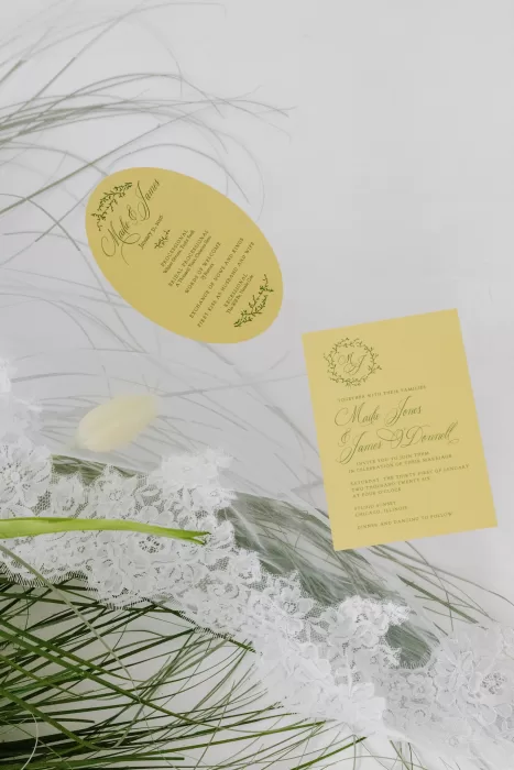Wedding invitation suite with lace, tulips and delicate greenery styled on white surface at Studio Sunset Chicago