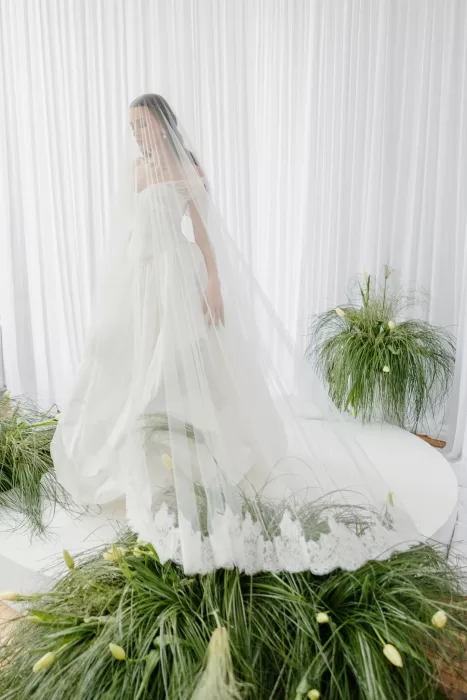 Bride wearing long veil standing on platform framed by flowing drapes and soft greenery at Studio Sunset Chicago