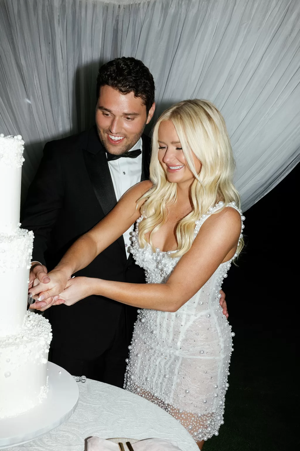 Newlyweds cutting their wedding cake together during the evening celebration.