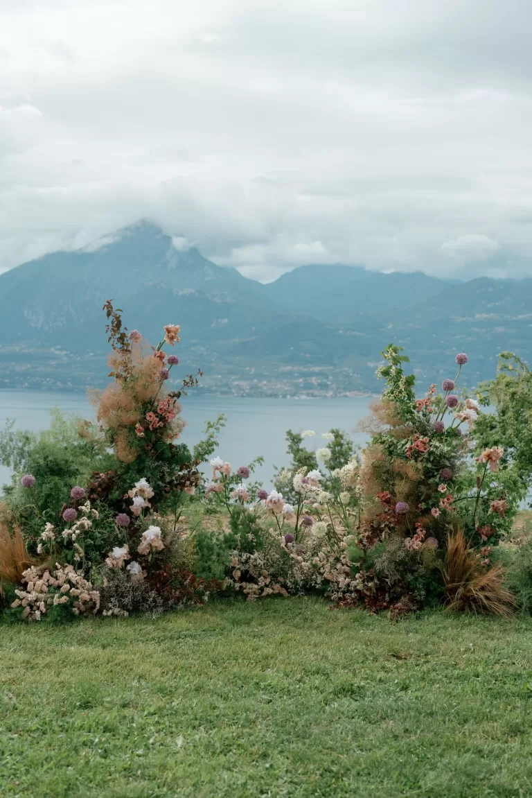 Romantic floral ceremony installation overlooking a lake and mountains at an outdoor destination wedding.