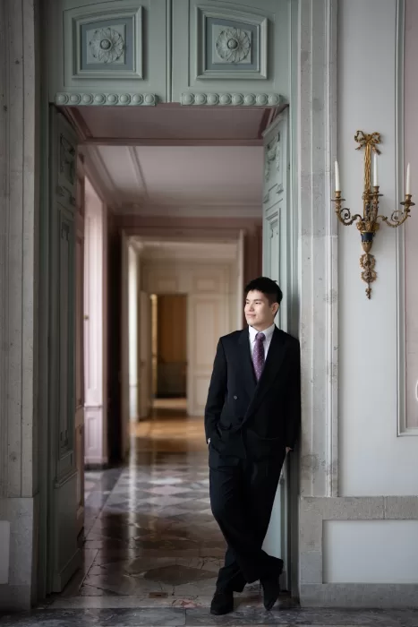 Groom leaning casually in a doorway of a refined interior with classical architectural details