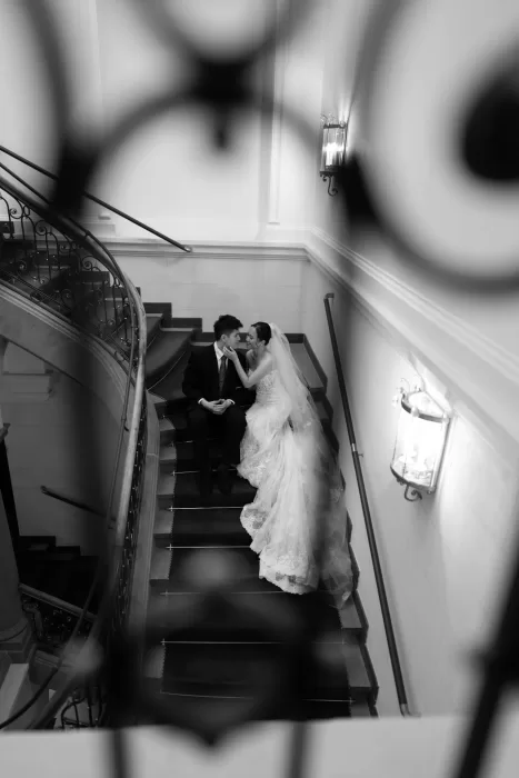 Couple sharing a quiet moment on a curved staircase captured through soft foreground blur