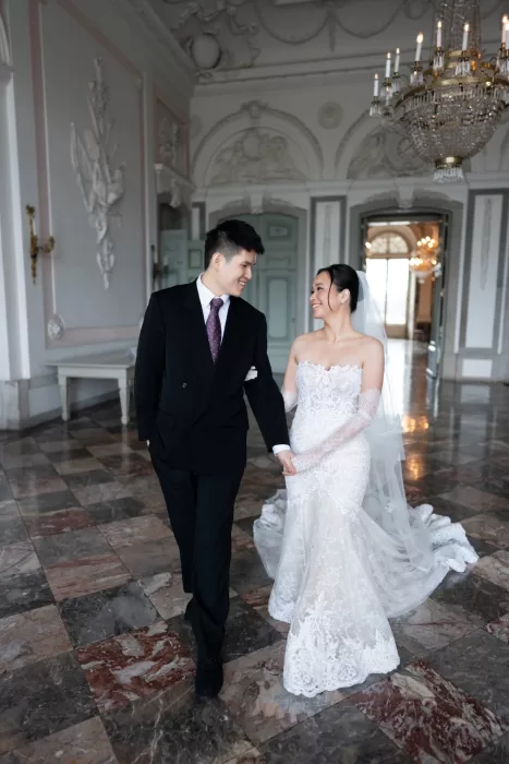 Bride and groom standing together on a curved staircase, viewed from above in a grand venue