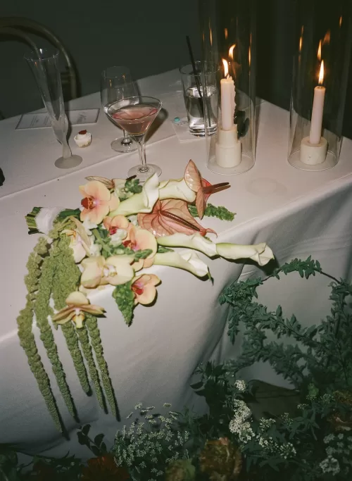 Candlelit table with cocktails and a cascading bouquet of orchids and anthuriums