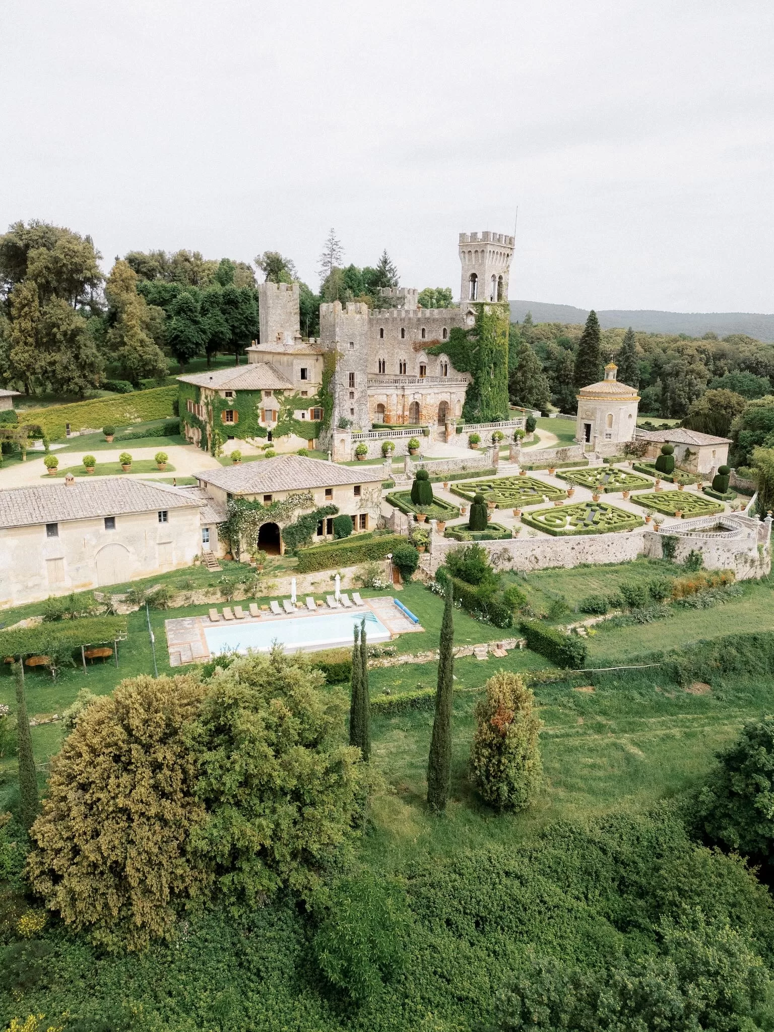 Aerial view of Castello di Celsa surrounded by Tuscan countryside and formal Renaissance gardens.