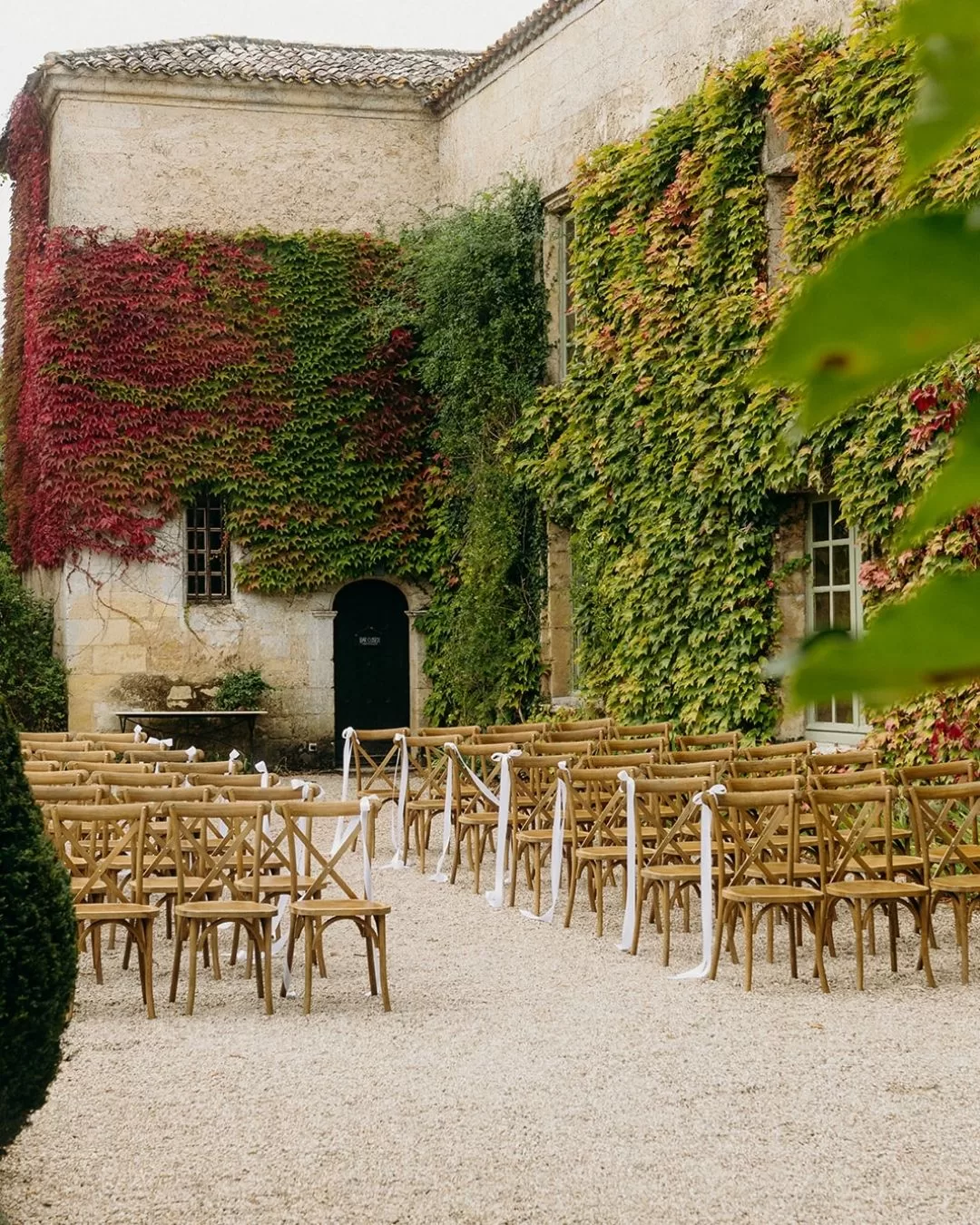 Outdoor wedding ceremony setup with wooden cross-back chairs and white ribbon accents at Château Rigaud.