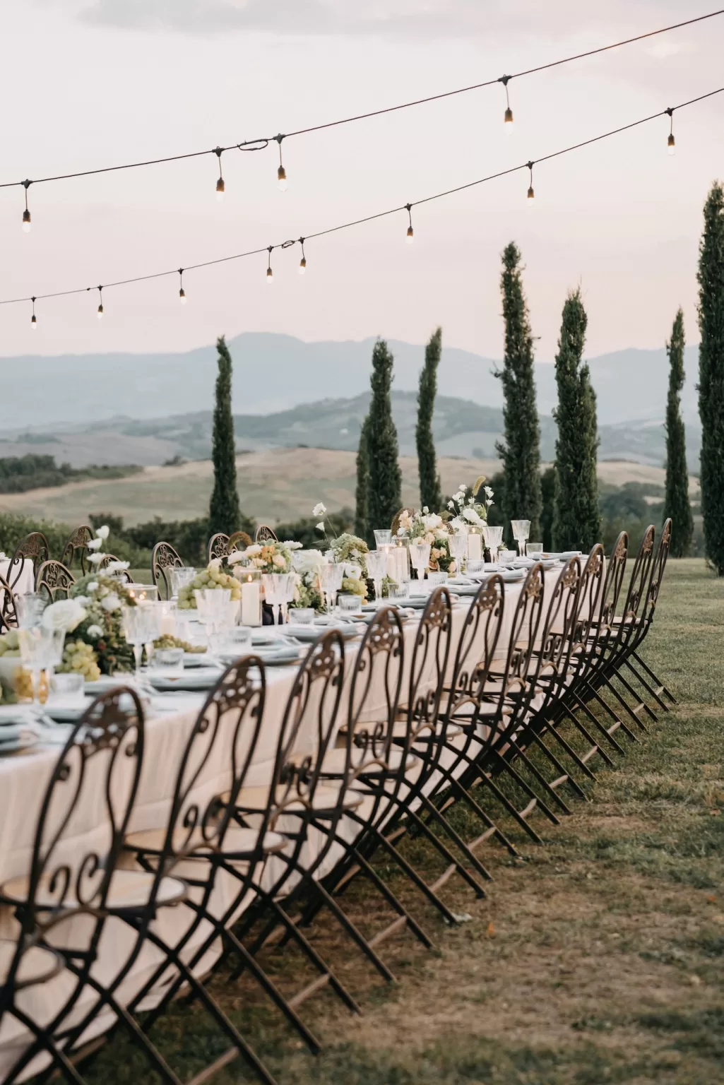 Long reception table with vineyard views and string lights in Tuscany
