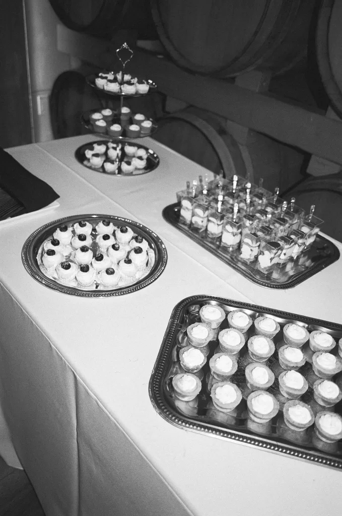 Mini desserts arranged on silver trays in a softly lit barrel room
