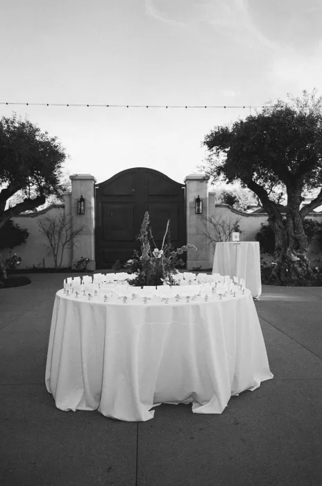 Round escort card table with sculptural florals set outside the venue gates