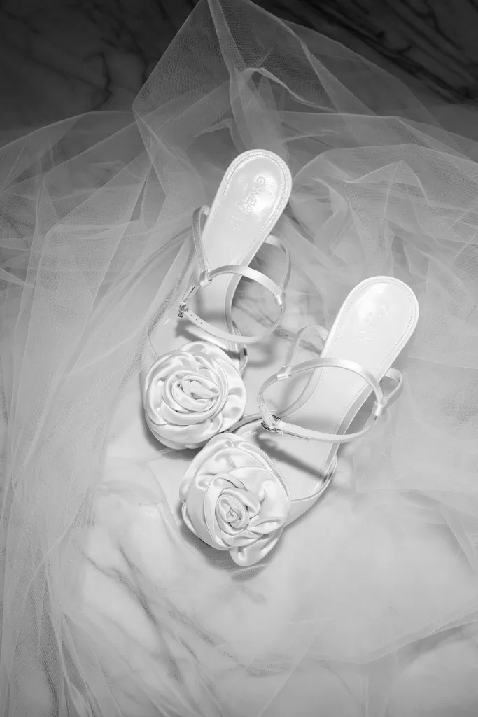 White bridal shoes with fabric flowers placed on veil at Finca Morneta