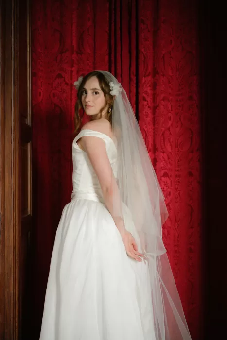 Bride portrait with veil against red textured wall inside Finca Morneta