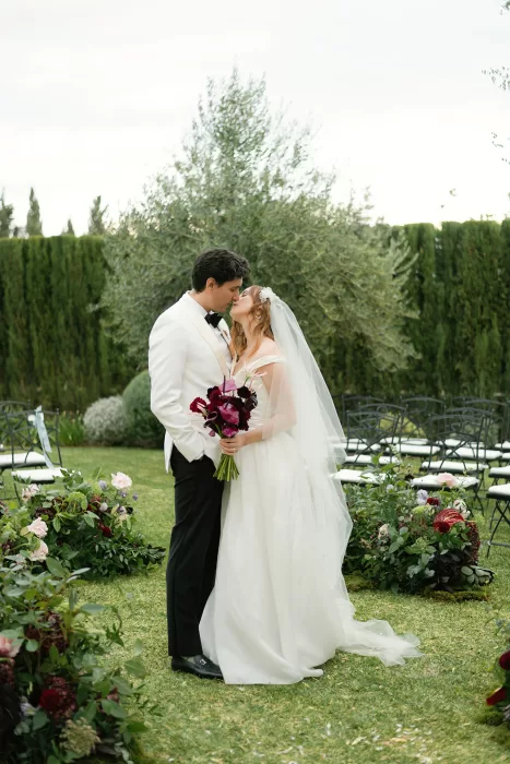 Bride and groom kissing after ceremony surrounded by flowers at Finca Morneta garden
