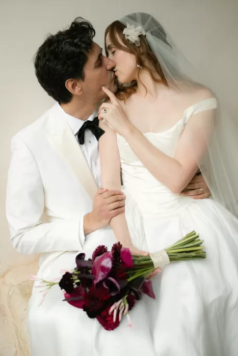 Bride and groom kissing in soft light holding bouquet at Finca Morneta