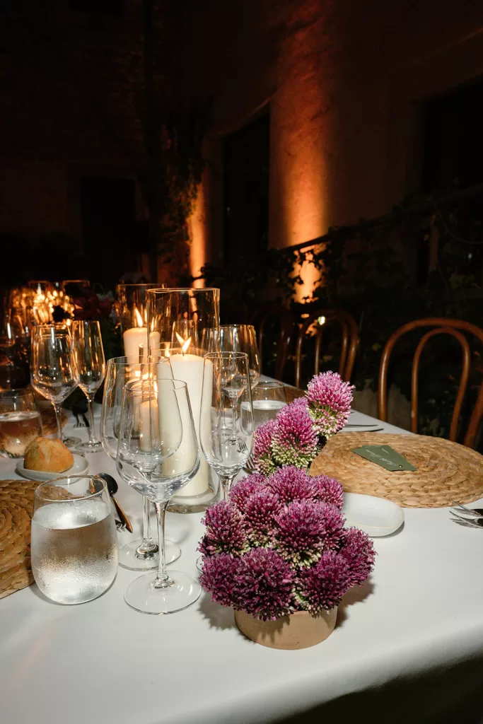 Reception table with candles, glassware and pink floral arrangement at Finca Morneta