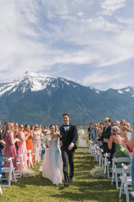 Bride and groom walking down aisle after ceremony with guests cheering at Fraser River Lodge