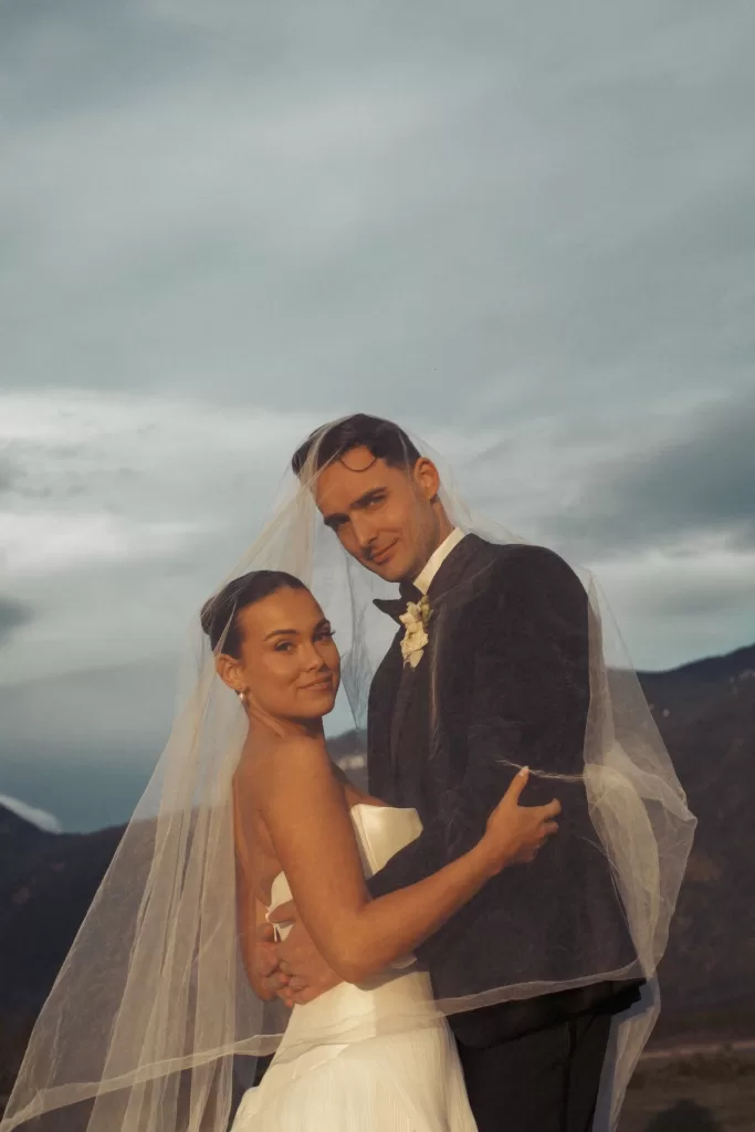 Bride and groom embracing beneath veil with moody sky at Fraser River Lodge