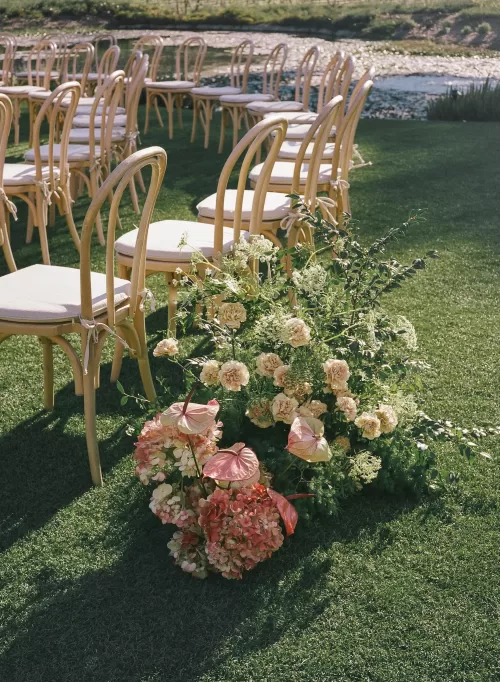 Floral arrangement beside ceremony chairs overlooking the lake in golden light