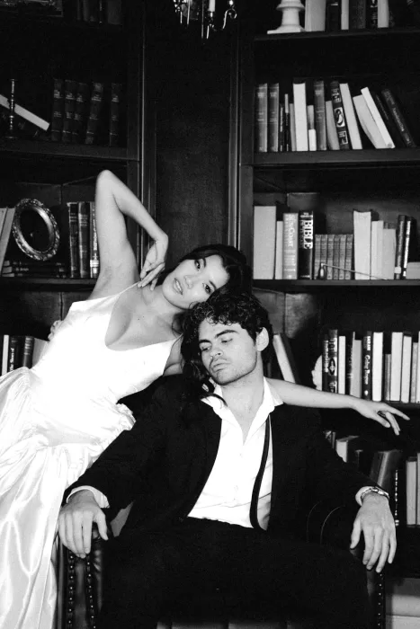 Black and white portrait of the couple in a moody library setting.
