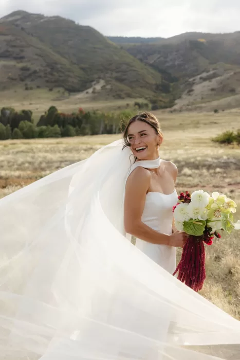 Bride smiling with her bouquet in the late afternoon light at The Manor House in Colorado.