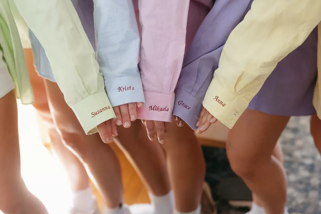 Bridesmaids showing embroidered getting ready shirts before the wedding at The Manor House.