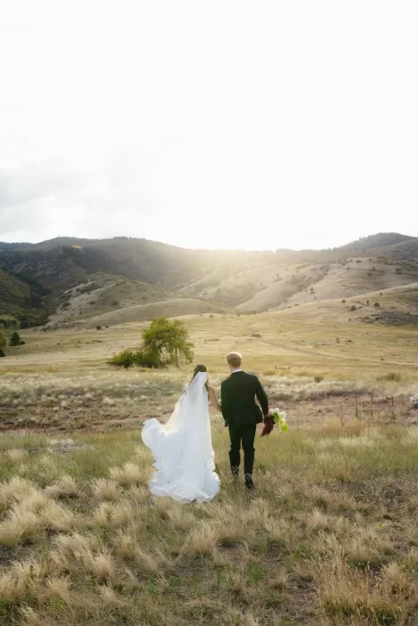 Bride and groom walking into the golden evening light in the open landscape near The Manor House in Colorado.