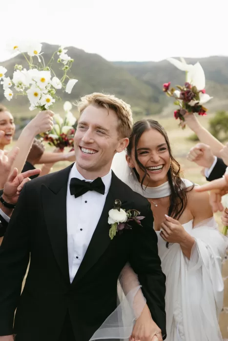 Newlyweds smiling as friends celebrate around them after the ceremony at The Manor House in Colorado.