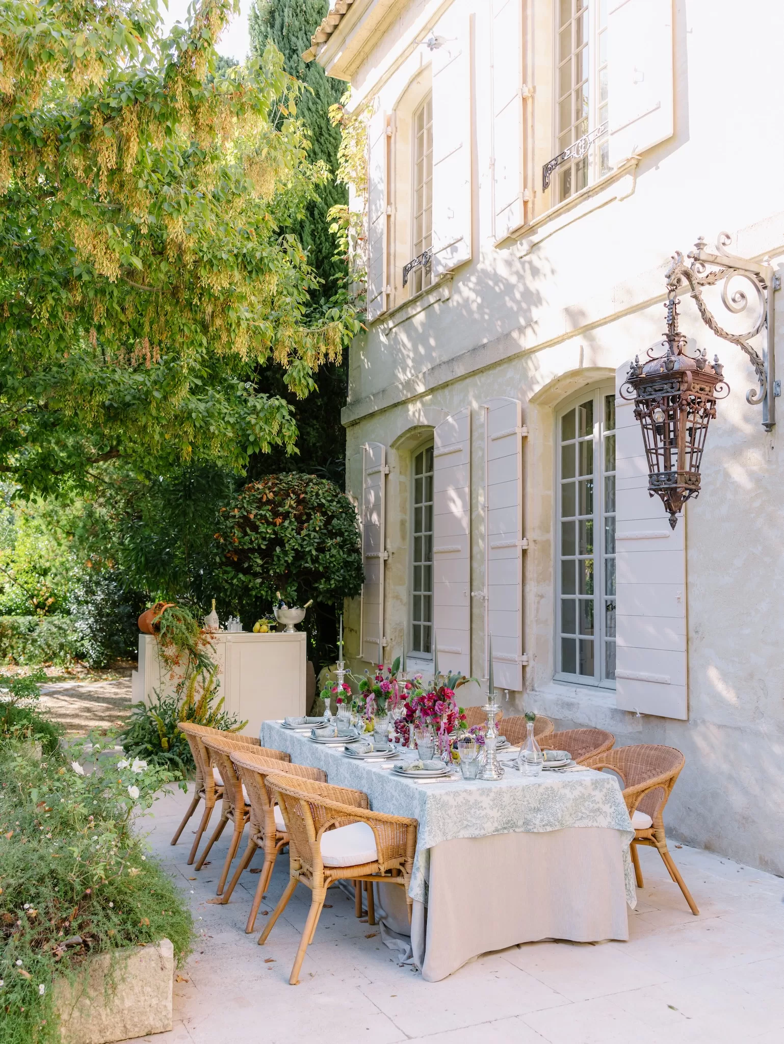 Long outdoor reception table set beside the villa facade and garden at Mas de Chabran.