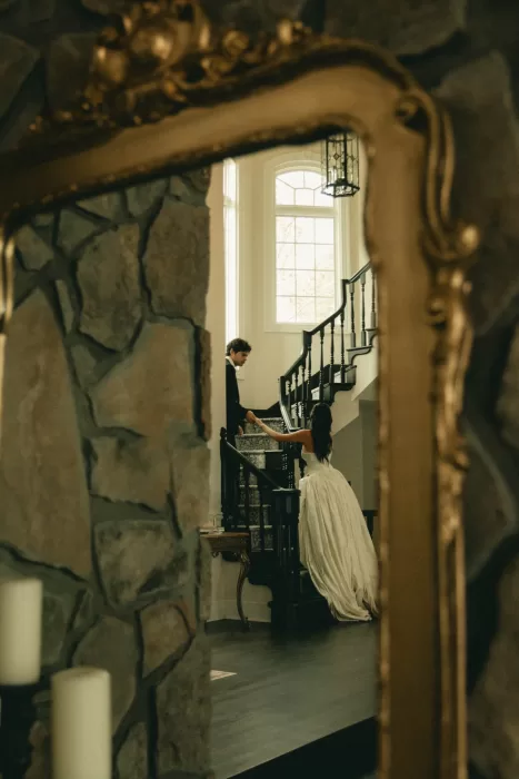 The couple are reflected in an ornate mirror beside the staircase.