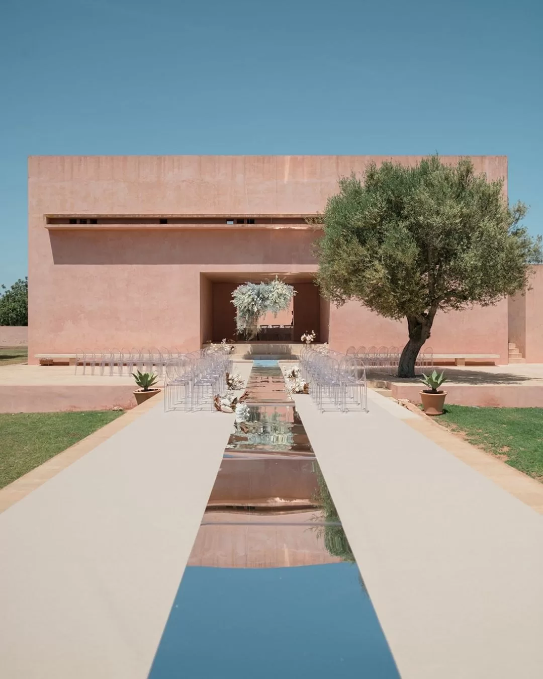 Minimalist outdoor ceremony with mirrored aisle and structured altar, captured by Puy Cermeño
