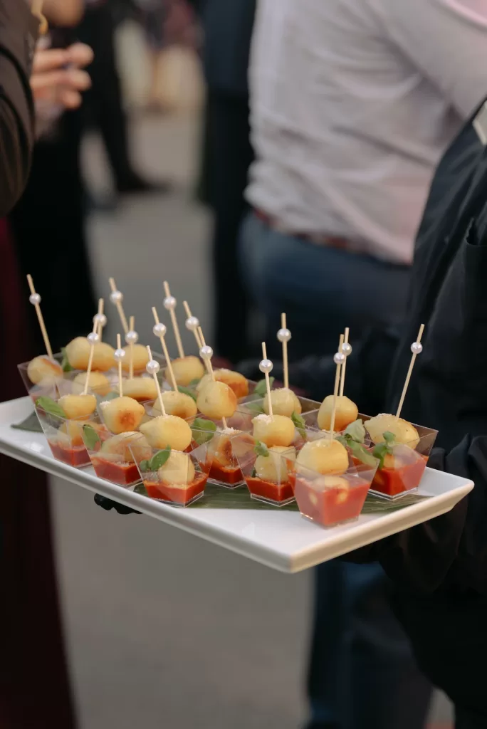 Tray of elegant cocktail bites with tomato base and skewered cheese balls during reception hour