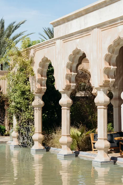 Sunlit Moorish arches reflected in water at Palais Namaskar, creating a serene courtyard setting