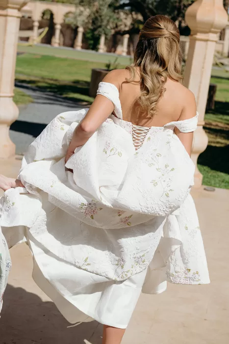 Bride lifting flowing embroidered wedding dress in sunlit courtyard at Palais Namaskar