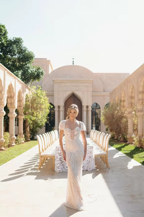 Bride walking through long reception table setup with arches and soft light at Palais Namaskar